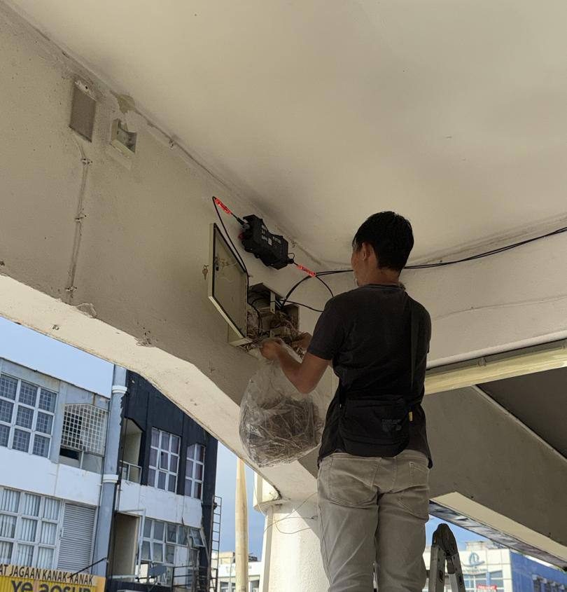 Technician installing an outdoor network distribution cabinet under a building awning