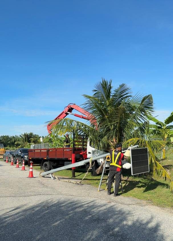 Crane truck installing a solar-powered utility pole on site